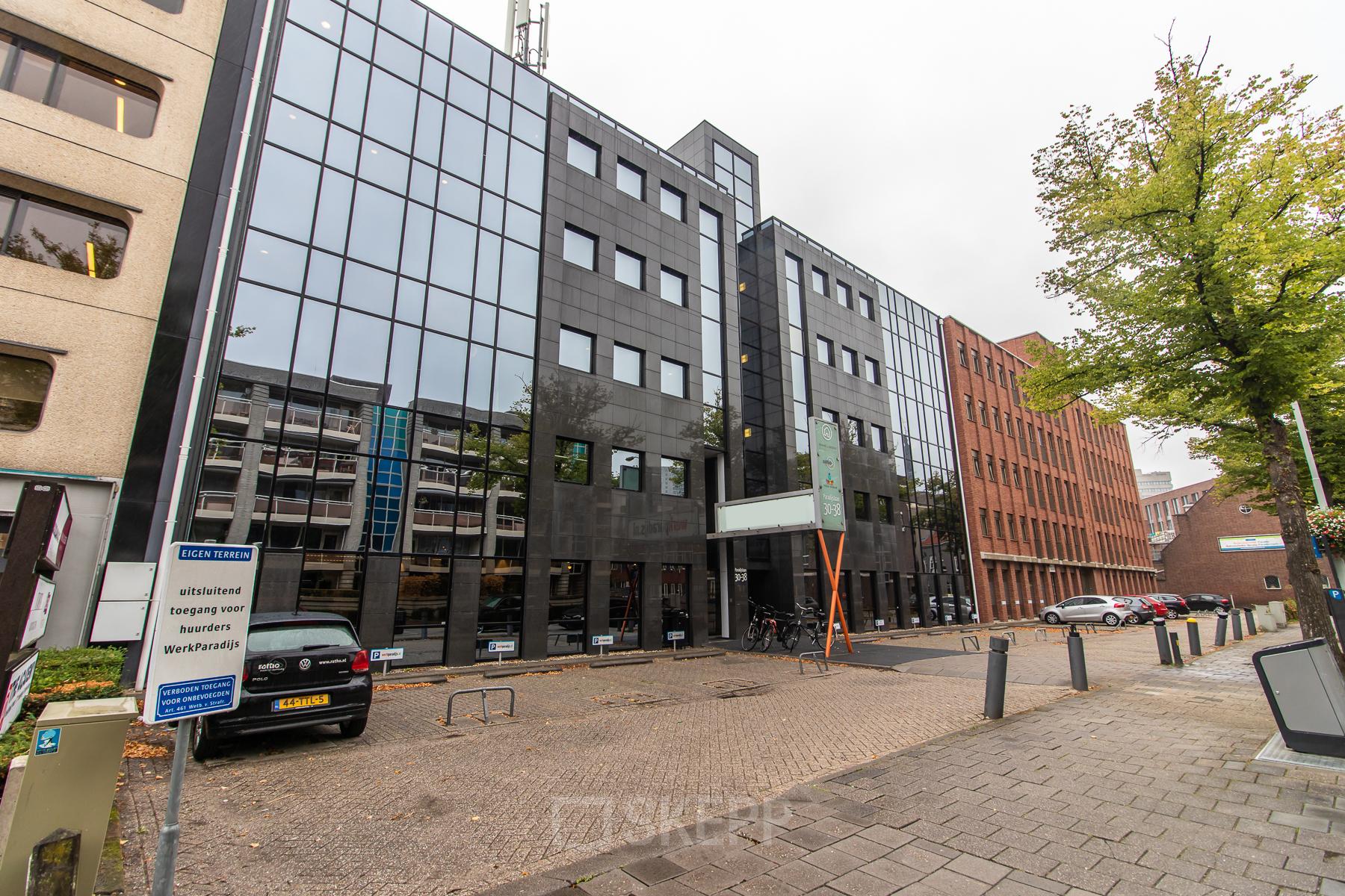 Exterior view of the office building at Paradijslaan 30-38 in Eindhoven Center, showcasing modern glass windows and entry area for office space rental.