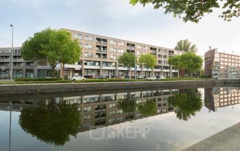 Exterior view of Kanaaldijk-Zuid 19 office site in Eindhoven Center with canal reflection and parked cars.