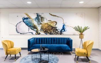 Stylish modern office lounge at Kanaaldijk-Zuid 19, Eindhoven Center, featuring vibrant seating and contemporary artwork, ideal for office space rental