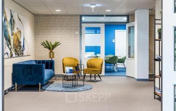 Modern office lounge area at Kanaaldijk-Zuid 19, Eindhoven Center, with stylish furniture and bright decor, highlighting available office space rental.