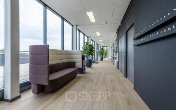 Spacious office corridor at Meerenakkerplein 1-10, Eindhoven De Hurk, featuring modern seating and large windows ideal for those looking to rent office space.