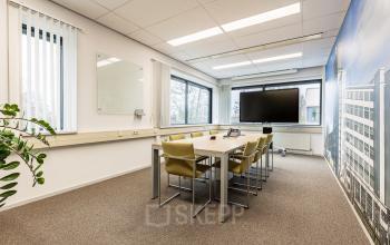 Bright office space with a conference table, chairs, and a large screen at Meerenakkerplein 11-20, perfect for office space rental in Eindhoven De Hurk.