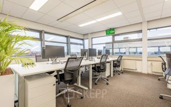 Bright office space with multiple desks and chairs, featuring large windows and ambient lighting, perfect for office space rental in Eindhoven De Hurk.