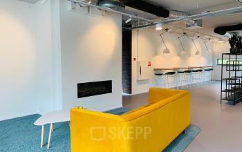 Modern office space with a yellow sofa, coffee table, high counter seating, and contemporary lighting at Hurksestraat 60, Eindhoven De Hurk, available for office space rental.