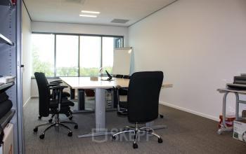 Office space rental at Hurksestraat 60, Eindhoven De Hurk, showing a bright room with a large table, office chairs, whiteboard, and shelves.