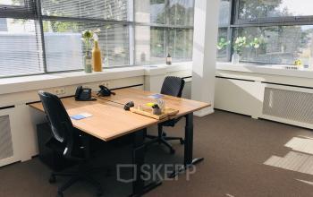 Bright office space rental at Hurksestraat 60, Eindhoven, featuring two desks, chairs, office equipment, and large windows with ample natural light.