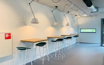 Minimalist office space at Hurksestraat 60, Eindhoven De Hurk with high stools and wooden counters along the wall, suitable for rent office space.