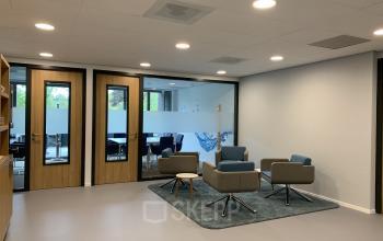 Interior of an office space rental at Hurksestraat 60, Eindhoven De Hurk, featuring a small meeting area with modern chairs, a rug, and glass-paneled doors.