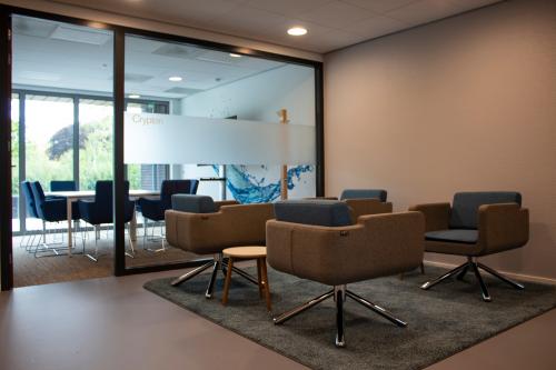 Cozy office space rental at Hurksestraat 60, Eindhoven De Hurk, featuring modern seating and a glass-walled conference room in the background.