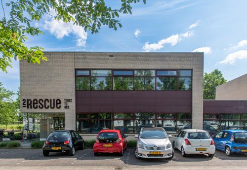 Exterior view of office building at Le Havre 114-127, Eindhoven North, featuring modern architecture and a parking area with several parked cars.