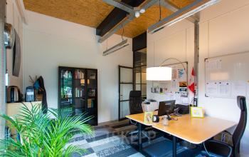 Furnished office space at Weegschaalstraat 3 featuring desks, chairs, bookshelves, and a plant for a productive workspace in Eindhoven North.