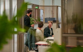 Modern workspace at Frederiklaan 10A, Eindhoven Strijp-S, featuring comfortable desks with colleagues engaged in a lively discussion. Ideal for office space rental.
