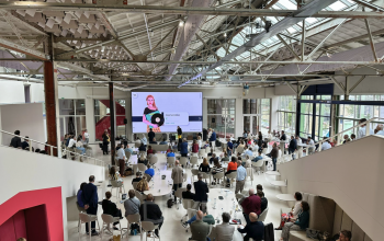 Interior view of Frederiklaan 10A, Eindhoven Strijp-S, featuring a spacious office area filled with people engaged in a business presentation. Ideal for office space rental in a vibrant setting.