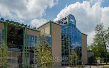 Exterior view of a modern office building at Frederiklaan 10A, Eindhoven Strijp-S, featuring large glass windows and surrounded by greenery. Perfect for office space rental.