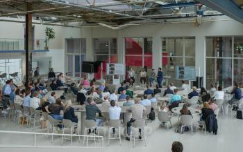 Spacious contemporary workspace at Frederiklaan 10A, Eindhoven Strijp-S, featuring a gathering of professionals engaged in a business presentation. Ideal office space rental for dynamic team activities.