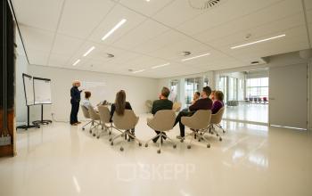 A modern conference room at Frederiklaan 10A, Eindhoven Strijp-S, featuring a group engaged in a business presentation. Bright and well-lit space ideal for office space rental.