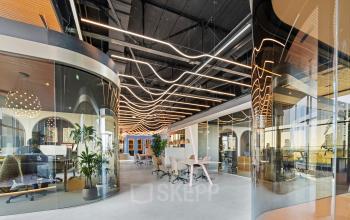 Contemporary office space with sleek glass partitions, stylish lighting, and modern furnishings, available for rent at Achtseweg Zuid 159R, Eindhoven Strijp-S.