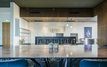 Chic office space rental in Eindhoven Strijp-S with a modern interior featuring a large table, stylish barstools, and contemporary decor at Achtseweg Zuid 159R.