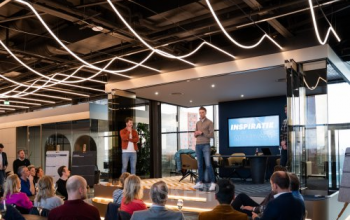 A modern, furnished office space in Eindhoven Strijp-S with people attending a presentation, ideal for office space rental.