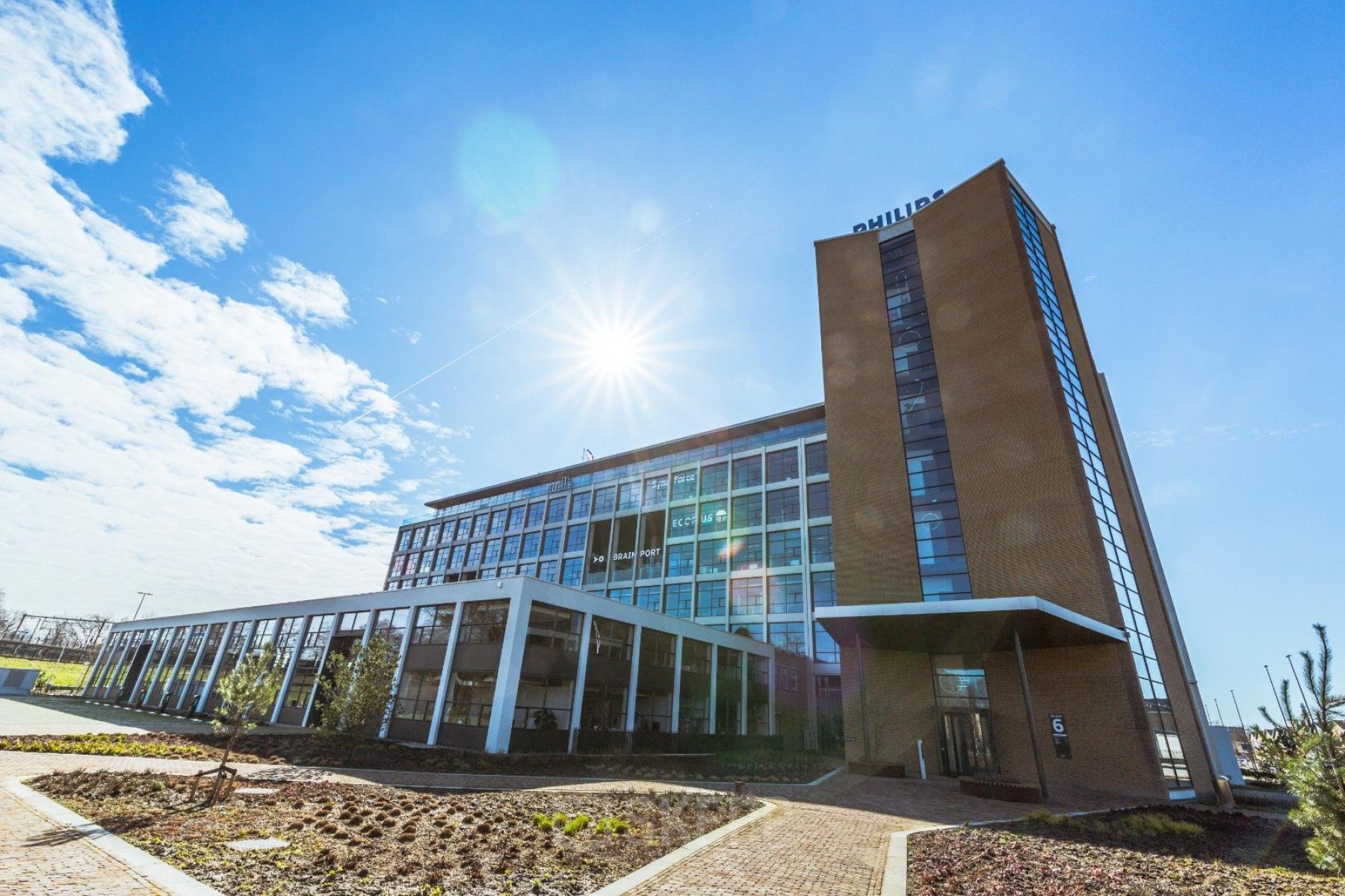 Exterior view of the office building at Achtseweg Zuid 159R, Eindhoven Strijp-S, showcasing a modern structure with clear skies, ideal for office space rental.