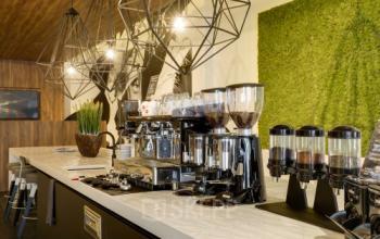 Modern office lounge area at Frederiklaan 10E, Eindhoven Strijp-S, featuring coffee machines and stylish lighting fixtures, ideal for office space rental.