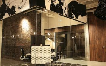 Modern office space at Frederiklaan 10E in Eindhoven Strijp-S with glass walls, stylish décor, and hexagonal flooring, available for office space rental.