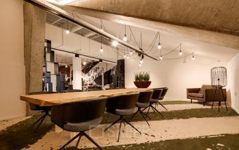 Modern office space at Frederiklaan 10E in Eindhoven Strijp-S with a long wooden table and chairs, suitable for a dynamic workspace environment. Ideal for office space rental.