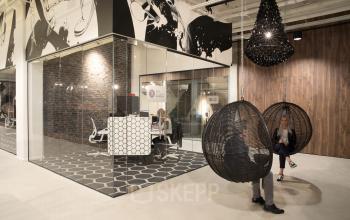 Modern office space for rent at Frederiklaan 10E, Eindhoven Strijp-S, featuring glass walls and stylish furnishings. People are engaged in business tasks at their desks.