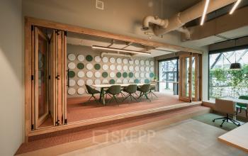 Modern office space rental in Eindhoven Strijp-S with a stylish meeting room featuring distinctive circular wall designs and contemporary furnishings.