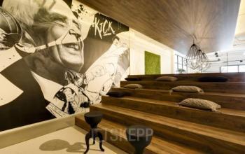 Stylish office space at Frederiklaan 10E, Eindhoven Strijp-S with tiered wooden seating, modern decor, and wall art. Ideal for creative workspace and office space rental.