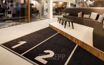 Modern office space for rent at Frederiklaan 10E, Eindhoven Strijp-S, featuring a stylish lounge area with seating and a unique runner-themed carpet.