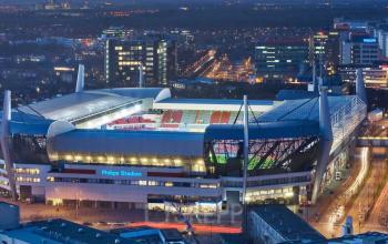 An evening aerial view of the Philips Stadium in Eindhoven, showcasing the surrounding city lights and structures.