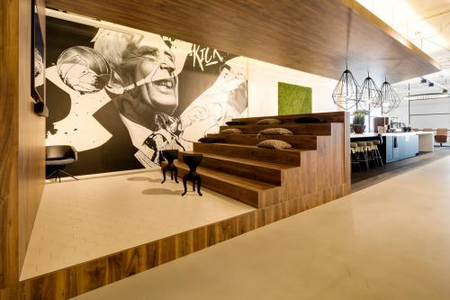 Contemporary office space at Frederiklaan 10E, Eindhoven Strijp-S, featuring wooden tiered seating with cushions and a stylish wall mural, available for office space rental.