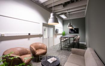 Furnished office space rental at Torenallee 20, Eindhoven Strijp-S, featuring modern seating with bar stools and a TV in a cozy setting.