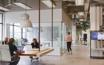 Office space rental at Torenallee 20, Eindhoven Strijp-S, featuring an open floor plan with modern furnishings and professionals engaged in collaborative work.