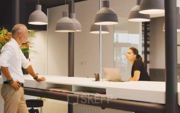 Office space rental area at Eindhoven Strijp-S with a man and woman interacting near a modern reception desk.