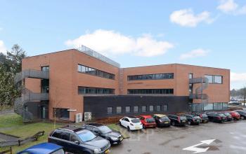 Exterior view of a modern office building at Boermarkeweg 58a in Emmen, showcasing ample parking and contemporary design, ideal for office space rental.