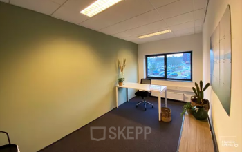 Office space rental at Boermarkeweg 58a in Emmen features a bright, furnished interior with a modern desk and chair, potted plants, and a view. Ideal for professionals seeking a peaceful workspace.