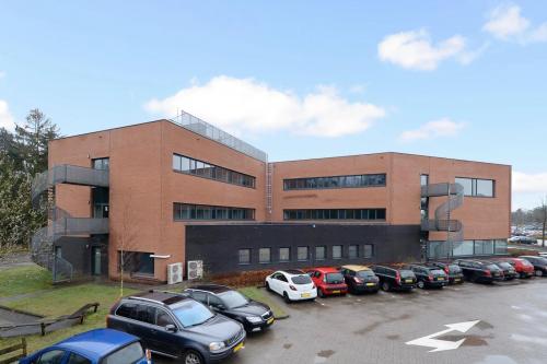 Exterior view of a modern office building at Boermarkeweg 58a in Emmen, showcasing ample parking and contemporary design, ideal for office space rental.