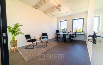 Bright office space with two desks, chairs, and a plant at Brouwerijstraat 1, Enschede. Ideal for rent office space seekers.