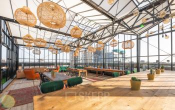 Spacious, sunlit lounge with modern decor and ample seating located at Brouwerijstraat 1, Enschede, perfect for office space rental.