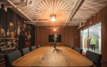Spacious conference room at Brouwerijstraat 1, Enschede, with a long wooden table, modern lighting, and artistic wall decor, ideal for office space rental.