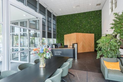 Modern reception area at Brandweerstraat 20-30 in Enschede featuring sleek furniture, greenery, and a welcoming desk. Ideal for office space rental seekers. The environment blends style with functionality seamlessly.
