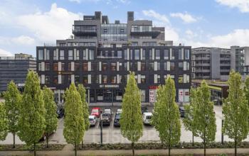 Exterior view of an office building located at Brouwerijstraat 10, in Enschede, featuring modern architecture with large windows and a parking lot in front.