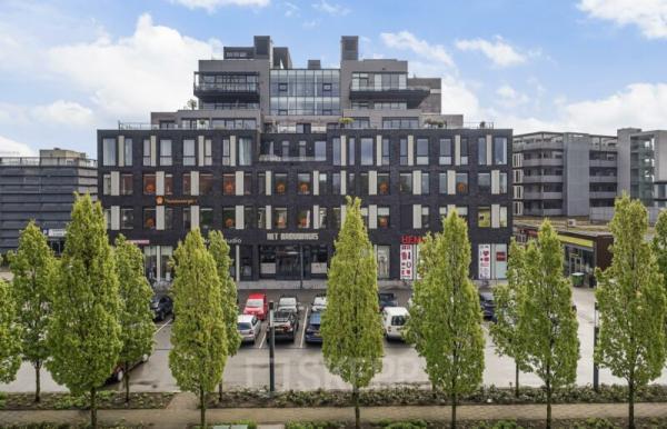 Exterior view of an office building located at Brouwerijstraat 10, in Enschede, featuring modern architecture with large windows and a parking lot in front.