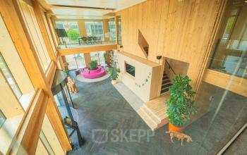 Wooden-interior office space on Moutlaan 1-23 in Enschede, showcasing a spacious, modern design with a mezzanine and large plants, ideal for office space rental.