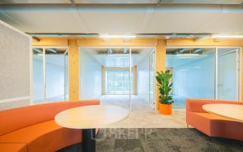 Modern office space for rent at Moutlaan 1-23, Enschede, featuring glass walls and stylish furniture with bright seating areas.