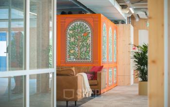 Stylish office space with modern decor and a vibrant partition at Moutlaan 1-23, Enschede, available for rent. The furnished area features comfortable seating alongside indoor plants.