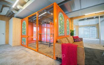 Bright office space with vibrant orange meeting pod and stylish seating, available for rent at Moutlaan 1-23, Enschede, ideal for office space rental.