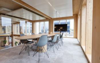 Modern conference room at Moutlaan 1-23, Enschede. Features a large table, chairs, and a wall-mounted screen, ideal for office space rental.